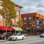 Crafton Heights neighborhood scene with brick buildings, storefronts, and parked cars, reflecting community pride and home aesthetics.