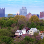 Historic rowhouses in Manchester with modern skyline backdrop, showcasing architectural heritage and urban development.