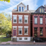 Historic brick rowhouse in Arlington Heights with a well-maintained facade, showcasing architectural details and surrounding greenery, representing home aesthetics and community charm.