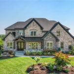 Beautiful stone house with a well-maintained roof, surrounded by vibrant landscaping, representing ideal home care and roofing maintenance in Bethel Park.