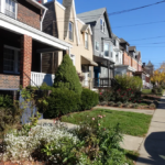 Row of well-maintained houses with diverse architectural styles and landscaping on Pittsburgh's North Shore, reflecting the importance of curb appeal and property value in roof maintenance.