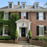 Historic brick home with colonial architecture, front steps, green ivy, and American flag, illustrating traditional curb appeal in Pittsburgh, relevant to roofing and exterior solutions.