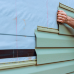 Person installing modern green siding on a historic home, emphasizing preservation of Squirrel Hill's architectural character.