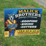Malick Brothers Exteriors yard sign featuring a cartoon dog mascot, promoting roofing, siding, and gutters services, with contact information.