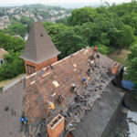 Workers performing roof maintenance on a commercial building, emphasizing seasonal roof preparation and inspection for winter readiness in Pittsburgh.