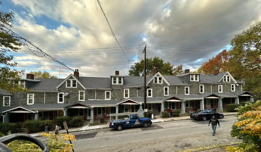 Row of historic multi-family homes with slate roofs and porches, showcasing the craftsmanship relevant to commercial roofing services in Pittsburgh.