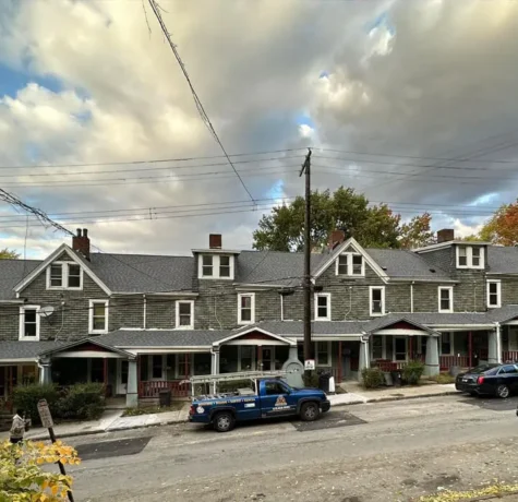 Row of commercial buildings with slate roofs and porches in Pittsburgh, showcasing potential roofing needs and maintenance considerations for property managers.