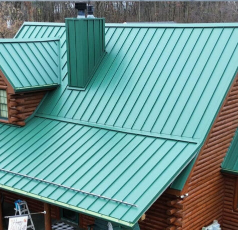 Metal roofing installation on a residential building, featuring a green, standing seam design, showcasing durability and energy efficiency relevant to Pittsburgh's climate.