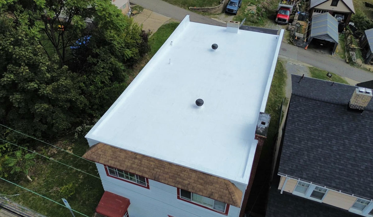 Aerial view of a flat TPO roofing system on a commercial building in Pittsburgh, showcasing its smooth white surface and ventilation features, relevant to the comparison of TPO and EPDM roofing materials.