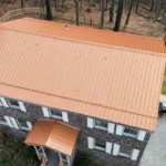 Aerial view of a residential building featuring a durable orange metal roof, emphasizing longevity and energy efficiency in roofing solutions.