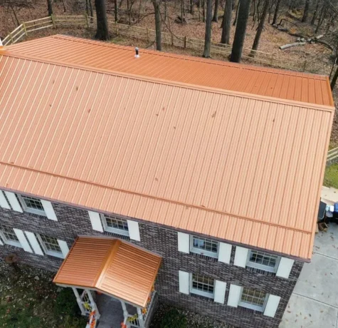 Aerial view of a residential home featuring a new orange metal roof, highlighting roofing materials and installation quality relevant to Pittsburgh homeowners and roofing services.