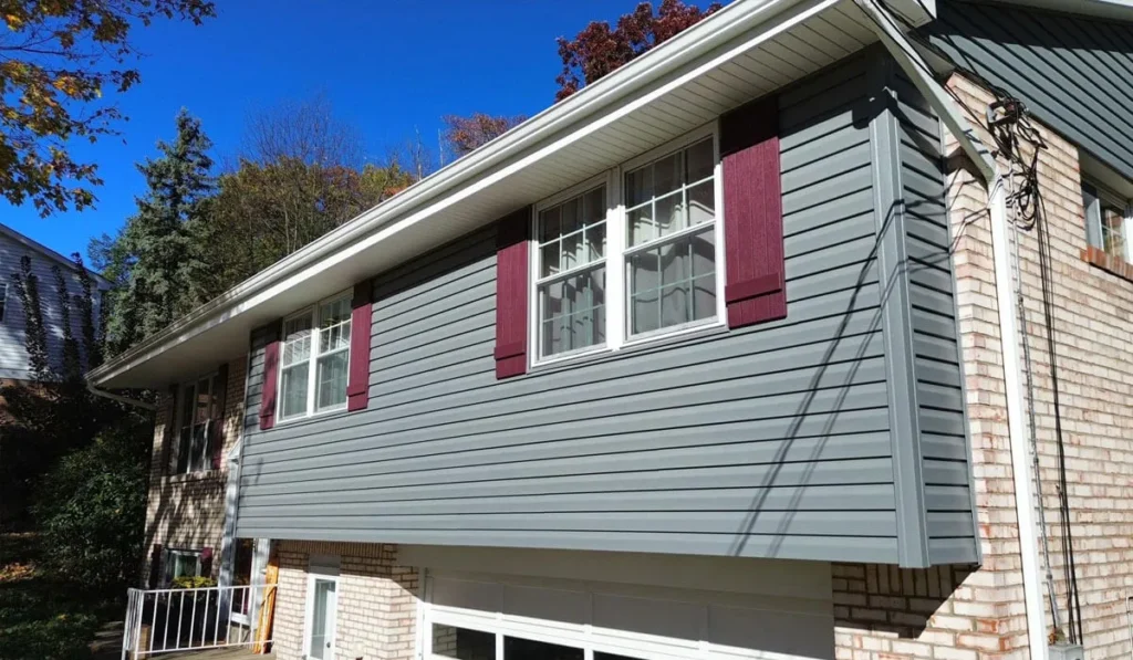 Gray vinyl siding on a home with burgundy shutters, showcasing exterior improvements relevant to homeowners insurance claims for storm damage.