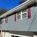 Gray siding with deep maroon shutters on a house, showcasing a harmonious exterior color combination that enhances curb appeal and reflects luxury design principles.