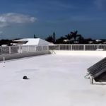 White silicone roofing system with a flat surface, showcasing proper installation and ventilation components, under a clear blue sky.