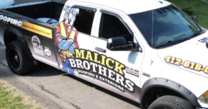 Malick Brothers Exteriors branded truck with logo and contact information, parked on a residential street, representing local roofing services for Pittsburgh homeowners.