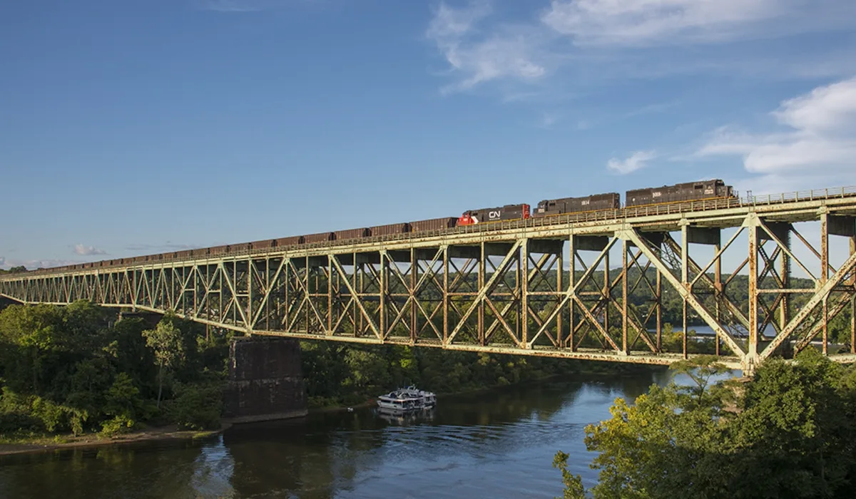 Soaring high above Harmar Township, PA, the southbound Bessemer and Lake Erie ore train from Conneaut crosses the massive bridge over the Allegheny River as it nears North Bessemer. The crew will leave their106 loads at the yard for the Union Railroad and return north with more empty hoppers for the ore dock on Lake Erie. Power for today's train is IC SD70's 1018 and 1034 along with CN SD60 5422.