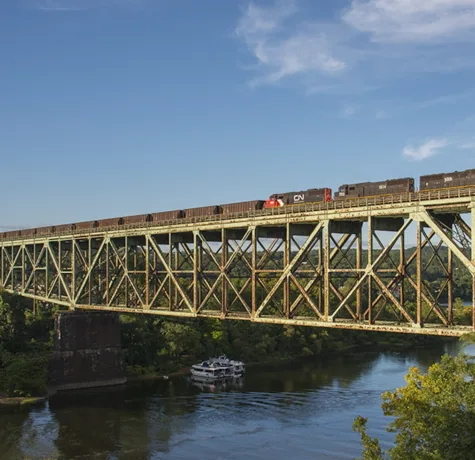 Soaring high above Harmar Township, PA, the southbound Bessemer and Lake Erie ore train from Conneaut crosses the massive bridge over the Allegheny River as it nears North Bessemer. The crew will leave their106 loads at the yard for the Union Railroad and return north with more empty hoppers for the ore dock on Lake Erie. Power for today's train is IC SD70's 1018 and 1034 along with CN SD60 5422.