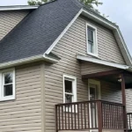 Residential home featuring a shingle roof, vinyl siding, and a front porch, illustrating quality roofing solutions for homeowners.