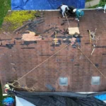 Roofers replacing a commercial roof with visible damage and maintenance work in progress, highlighting the importance of roof investment and maintenance strategies.