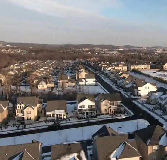 Aerial view of residential neighborhood in Cranberry Township with snow-covered rooftops and tree-lined streets, showcasing homes that may require roofing services.