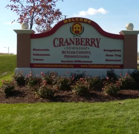 Cranberry Township welcome sign in Butler County, Pennsylvania, featuring the township name, website URLs (www.cranberrytownship.org and www.visitbutlercounty.com), and greetings in various languages. This sign represents the vibrant and diverse community that Malick Brothers Exteriors proudly serves with expert roofing services.