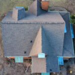 Aerial view of a residential roof with multiple peaks and chimneys, showcasing shingles and potential areas for inspection, relevant to roofing services in Pittsburgh.