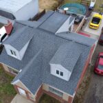Aerial view of a residential home in Pittsburgh featuring new gray roofing and multiple gable structures, highlighting quality siding installation by Malick Brothers Exteriors.