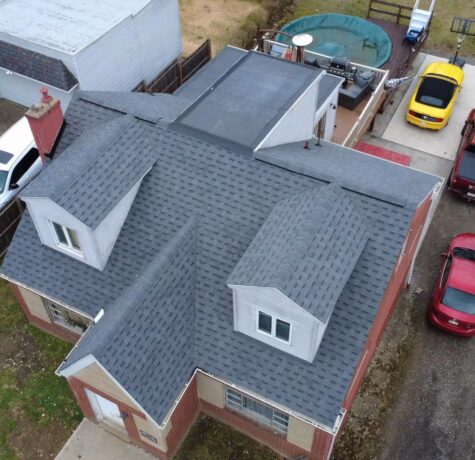 Aerial view of a residential home showcasing a newly installed gray asphalt shingle roof, highlighting the roofing structure and surrounding outdoor area, relevant to Malick Brothers Exteriors' roofing services in Pittsburgh.