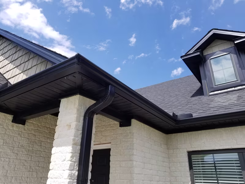 Soffit and roof overhang showcasing black trim and downspout on a Pittsburgh home, emphasizing ventilation and aesthetic appeal.