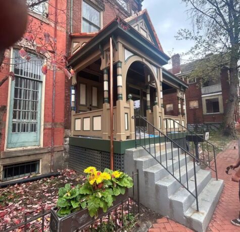 Renovated porch of a historic building with decorative architecture, featuring a flower bed and brick walkway, relevant to Malick Brothers Exteriors' commercial roofing and exterior solutions.