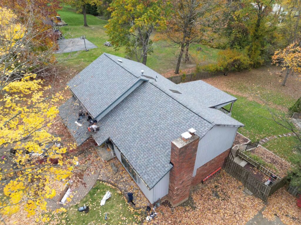 Aerial view of a residential home in Pittsburgh with a newly installed energy-efficient roof, surrounded by autumn foliage and a well-maintained yard, reflecting 2025 exterior home trends.
