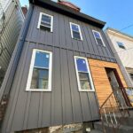 Residential home exterior with modern gray siding and wooden entrance, showcasing quality craftsmanship relevant to roofing and home improvement services in Pittsburgh.