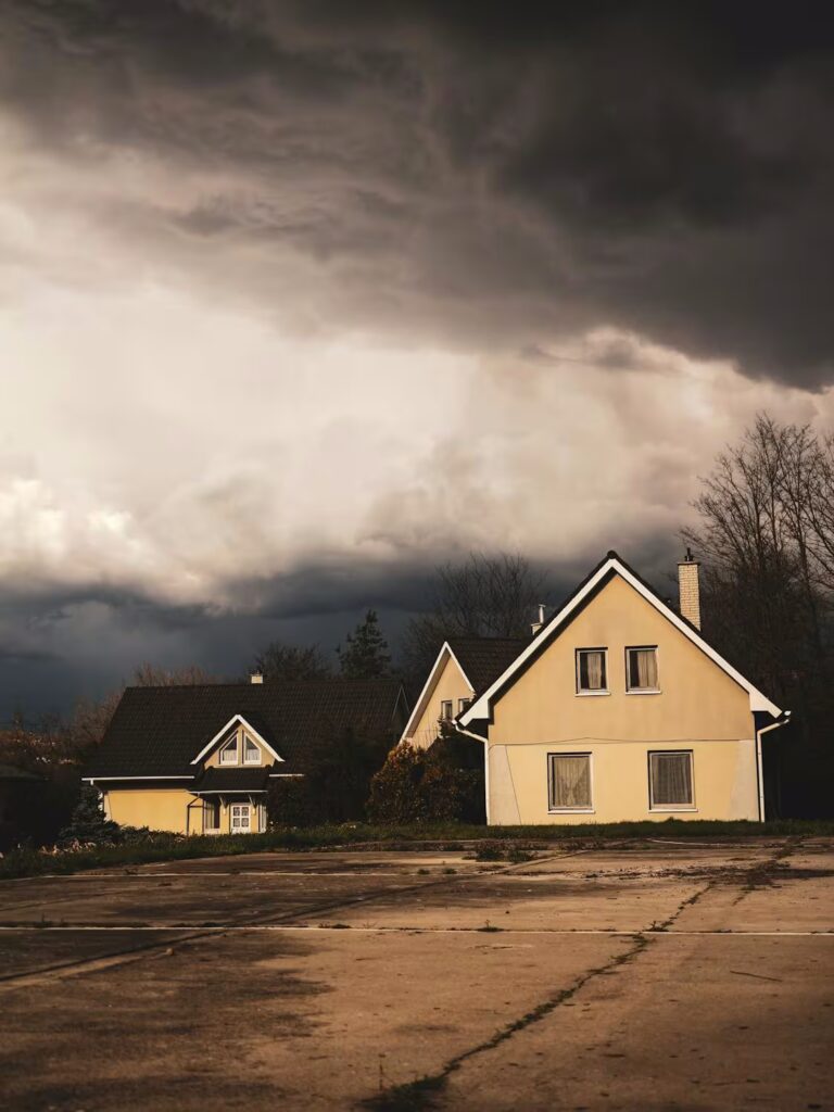 Residential home with dark storm clouds approaching, highlighting the need for roof and siding storm preparation.