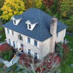 Aerial view of a residential home with a dark shingle roof, surrounded by autumn foliage, illustrating roofing maintenance and aesthetics relevant to homeowners in Wexford and Cranberry Township.