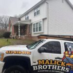Malick Brothers Exteriors truck displayed on a residential renovation site highlighting ongoing roofing and siding work