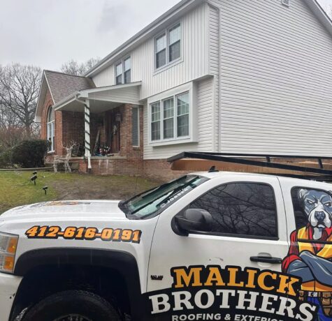Malick Brothers Exteriors truck displayed on a residential renovation site highlighting ongoing roofing and siding work