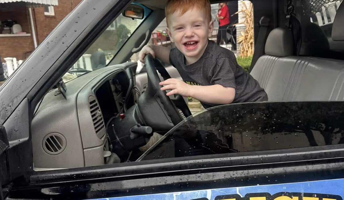 Child smiling and playing in the driver's seat of a vehicle, showcasing joy and innocence, with a focus on family-friendly experiences in Pittsburgh.