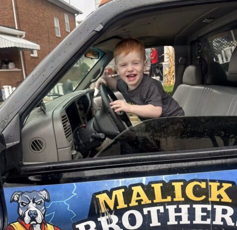 Smiling child in driver's seat of Malick Brothers Exteriors vehicle, showcasing family-friendly service and community engagement in Pittsburgh.