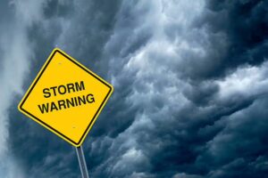 Storm warning sign against dark, ominous clouds, highlighting the impact of severe weather on roofing durability in Pittsburgh.