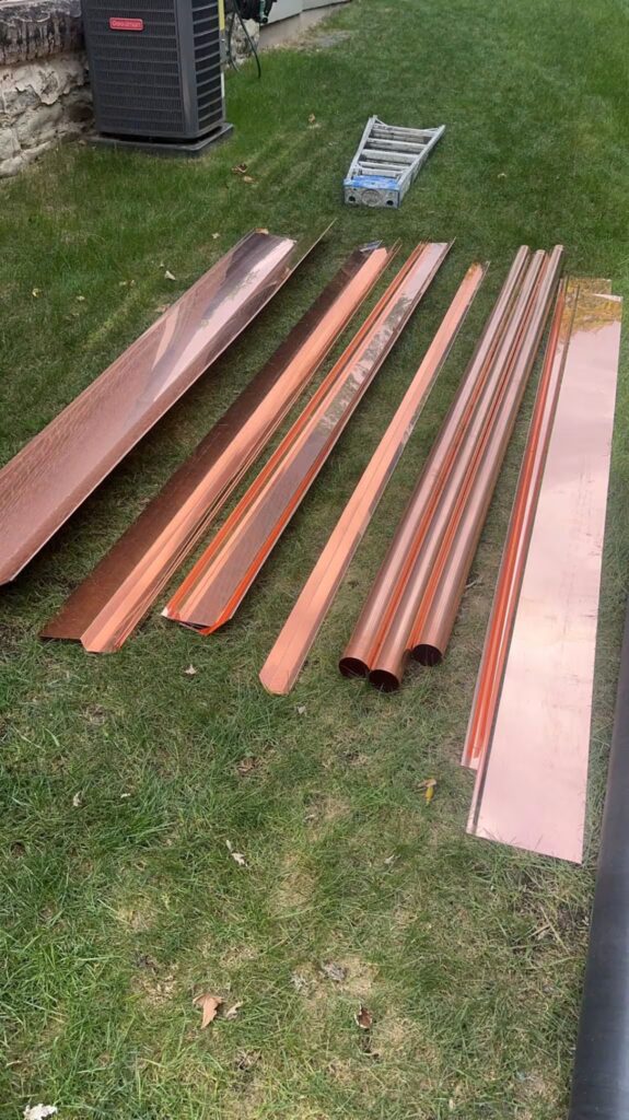 Copper roofing materials and components arranged on grass, showcasing durability and aesthetic appeal for roofing solutions in Pittsburgh.