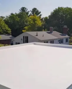 Flat PVC roof surface with a view of residential buildings and trees, illustrating durable roofing solutions suitable for commercial and industrial applications.