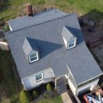 Aerial view of a residential home with gray asphalt shingles, featuring multiple gables and dormer windows, showcasing roofing quality and design for Pennsylvania homes.