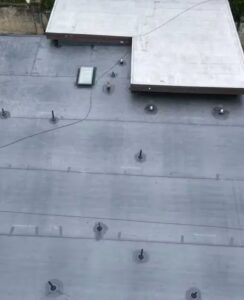 Rubber roofing installation on a flat roof with visible drainage features and skylight, illustrating seamless waterproofing and durability for Pittsburgh homes.