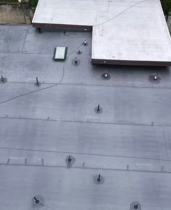 Rubber roofing installation on flat roof in Pittsburgh, featuring multiple fasteners and a skylight, highlighting durable and low-maintenance roofing solution.