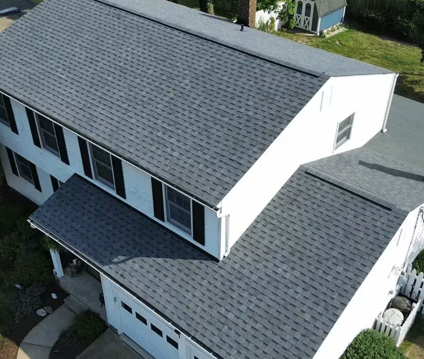 Aerial view of a house featuring a newly installed asphalt shingle roof, showcasing gray shingles and white siding, relevant to roofing services and costs in Pittsburgh.