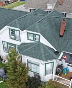 Aerial view of a residential roof featuring green shingles, highlighting the multi-angled structure and chimney, relevant to considerations for roof inspection and maintenance by Malick Brothers Exteriors.