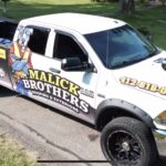 Malick Brothers Exteriors branded truck parked on a residential street, showcasing the company's logo and contact information, emphasizing local roofing services in Pittsburgh.
