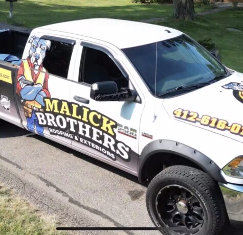 Malick Brothers Exteriors branded truck featuring a cartoon dog mascot, parked on a residential street, promoting roofing and exterior services in Pittsburgh.