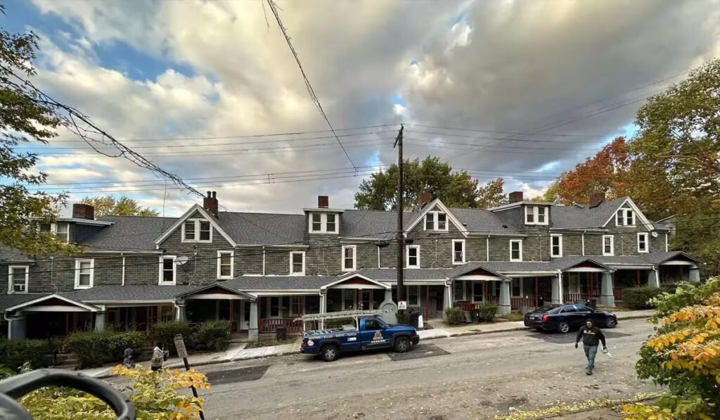 Row of residential buildings with new roofs, showcasing proper drainage and maintenance, under a cloudy sky in Pittsburgh.