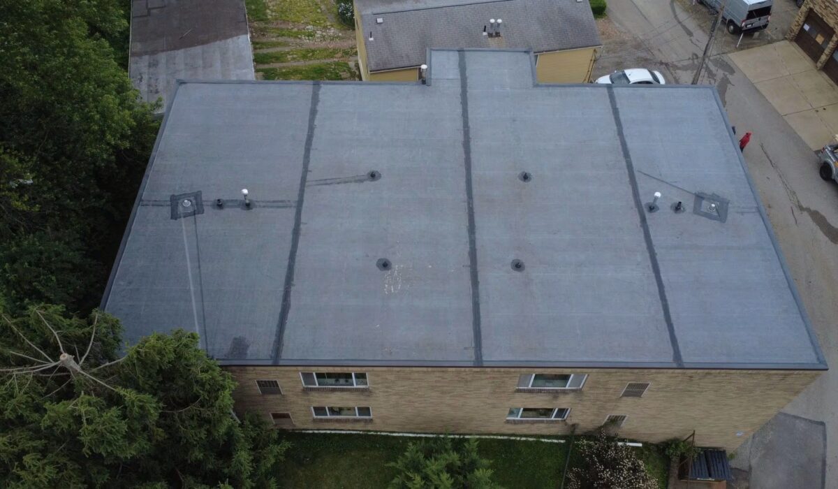 Aerial view of a commercial flat roof with membrane roofing system, showcasing durability features and ventilation elements, relevant to Pittsburgh's climate and commercial roofing solutions.